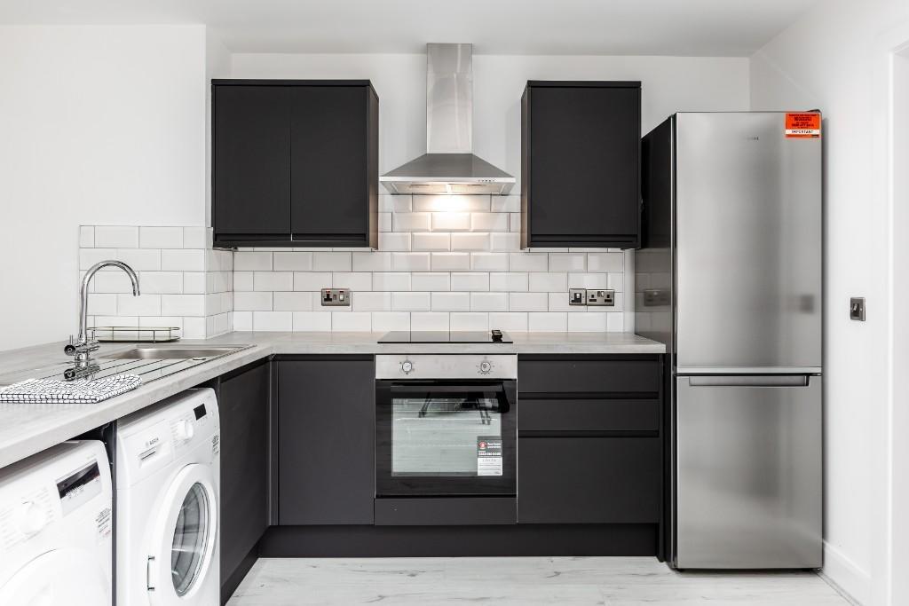 Modern kitchen featuring sleek black cabinetry,...
