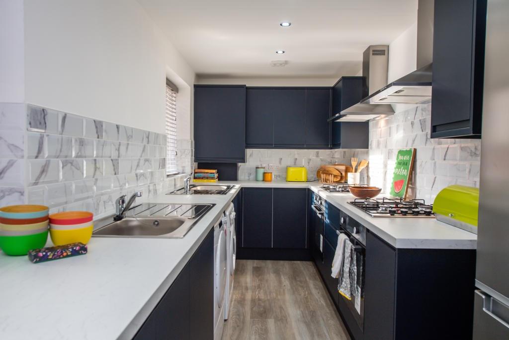 A modern, tidy kitchen featuring dark cabinetry...