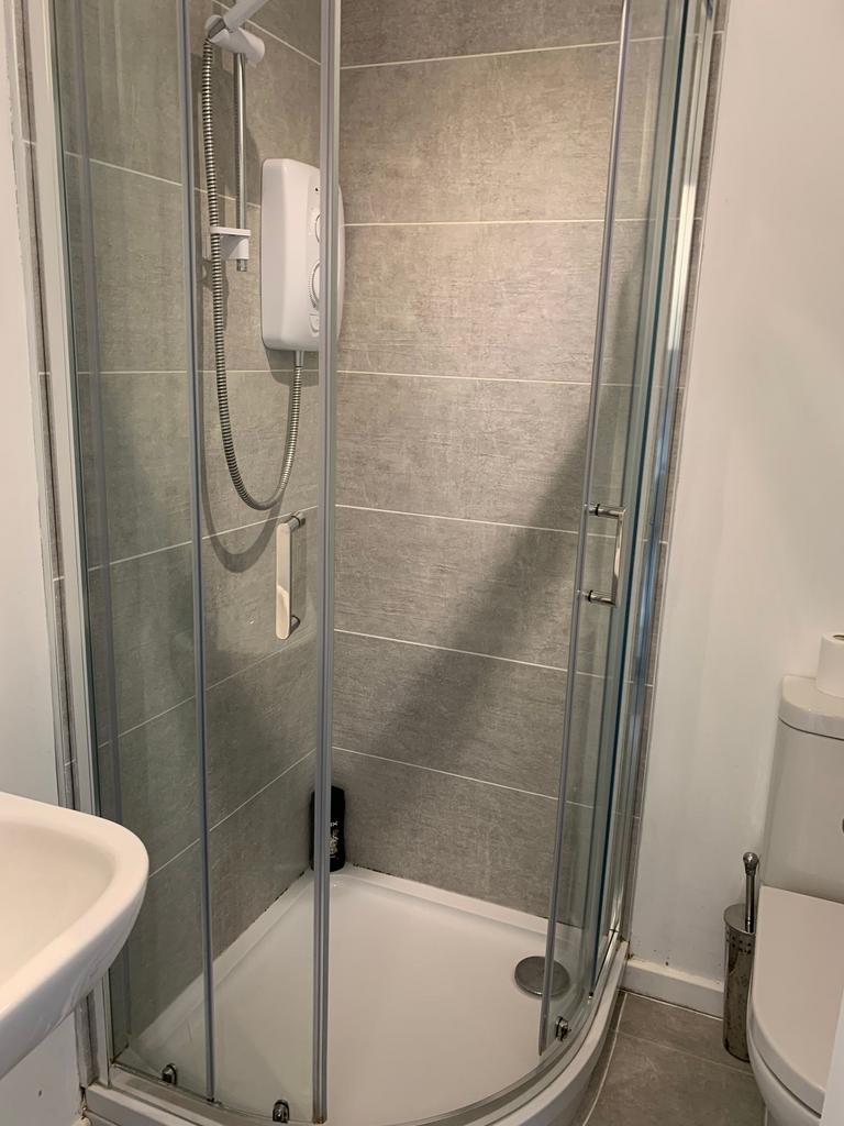 Modern tiled bathroom with a curved glass showe...