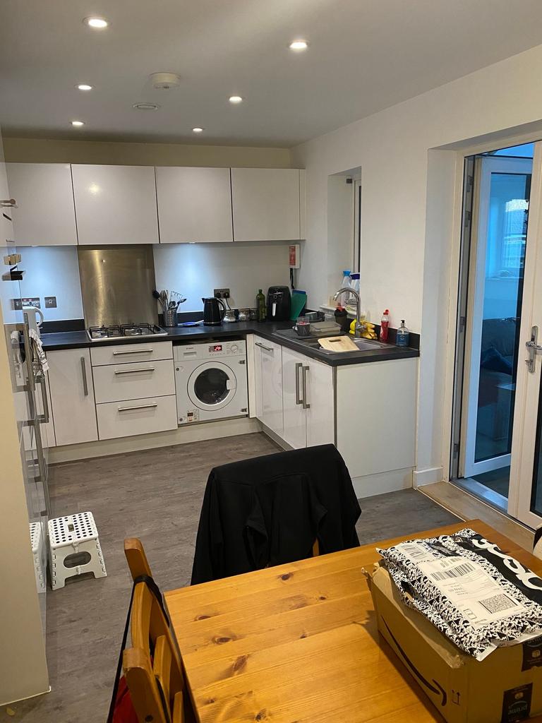 Modern fitted kitchen with white cabinets, blac...