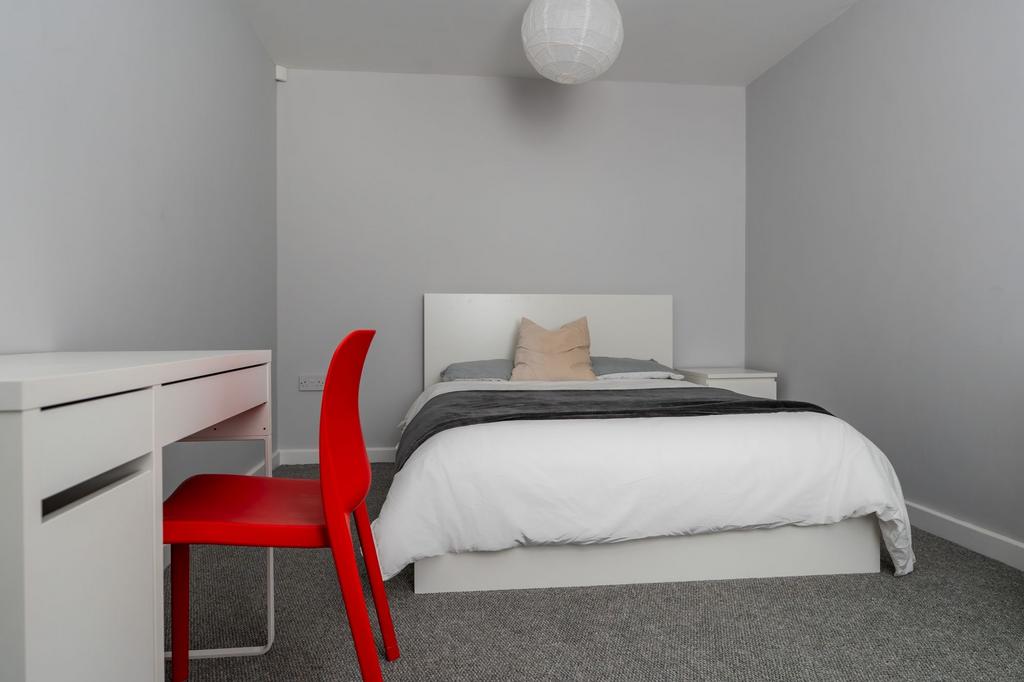 A clean and well-lit student bedroom featuring ...