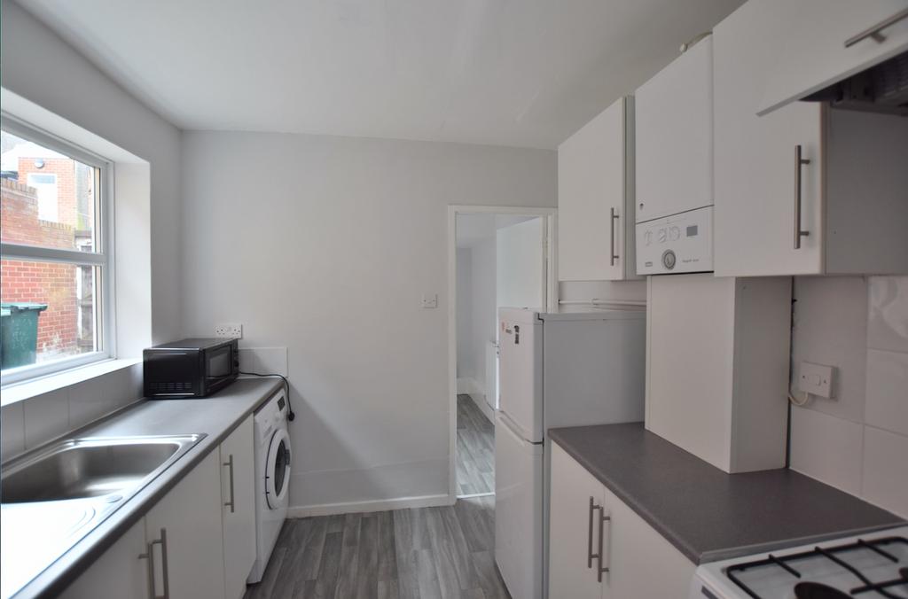 Bright, modern galley kitchen with white cabine...