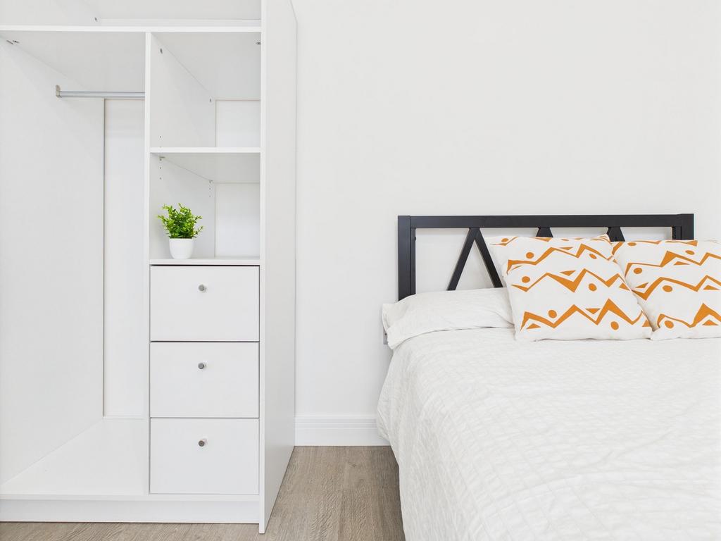 A bright, modern bedroom featuring a neatly mad...