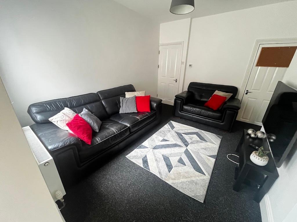 Bright, tidy living room with black leather sof...