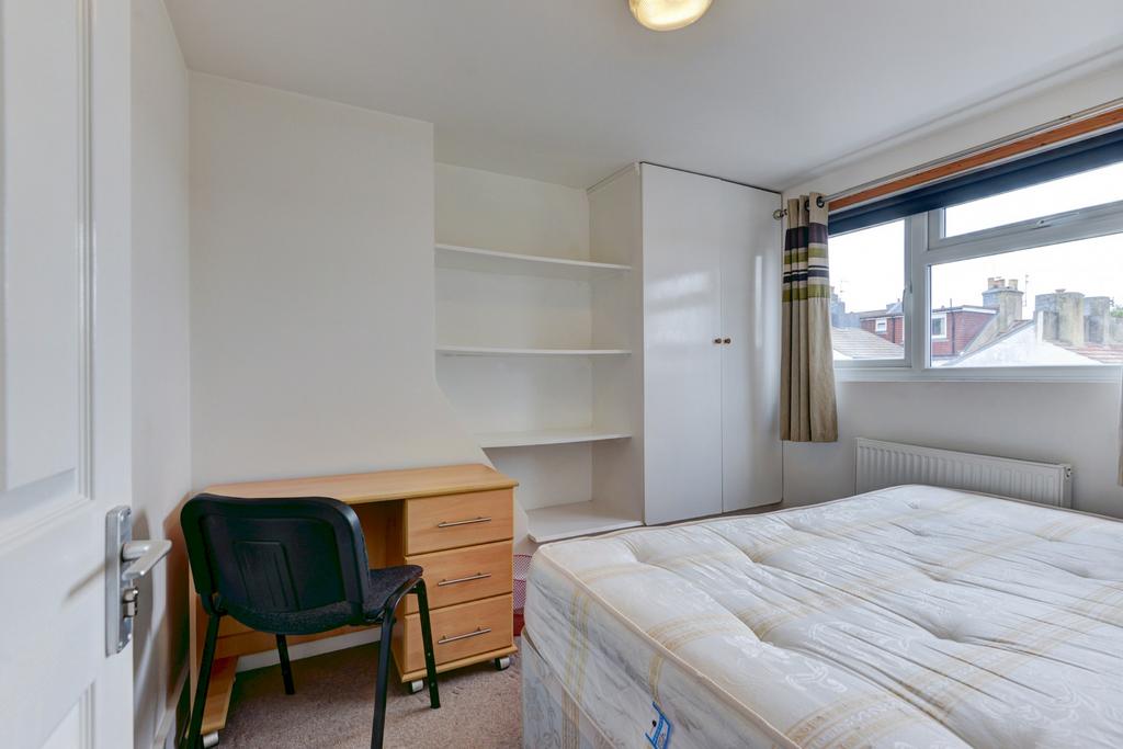 A bright and tidy bedroom featuring a large win...