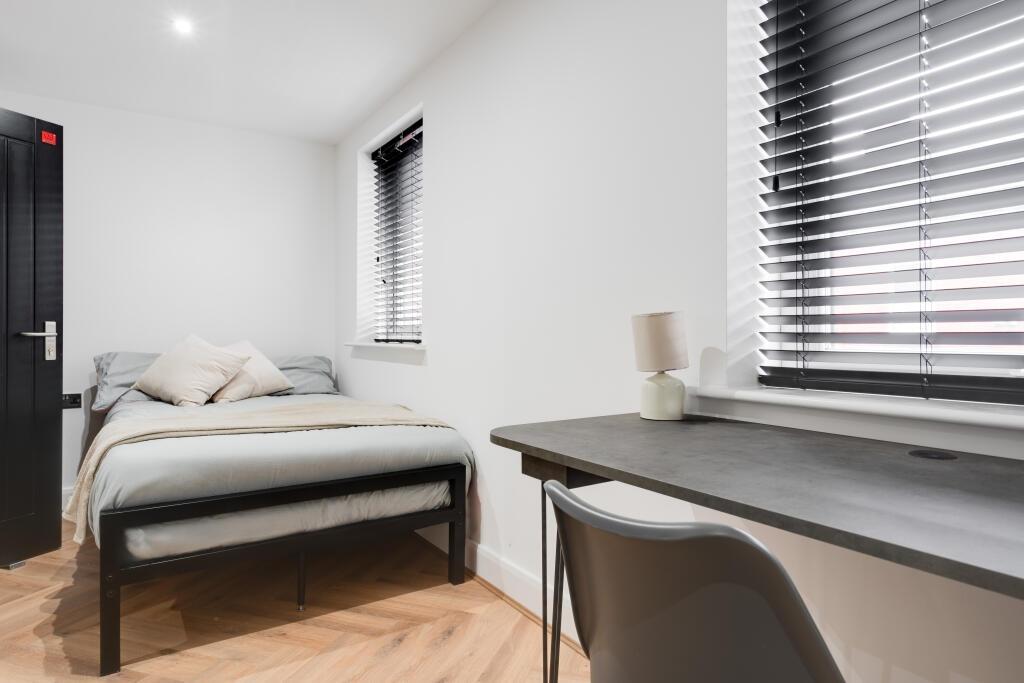A bright and tidy bedroom featuring a comfortab...
