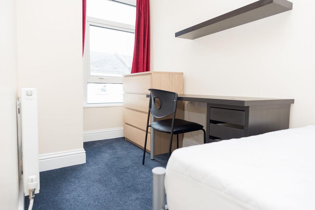 Bright, simply furnished bedroom with a study d...