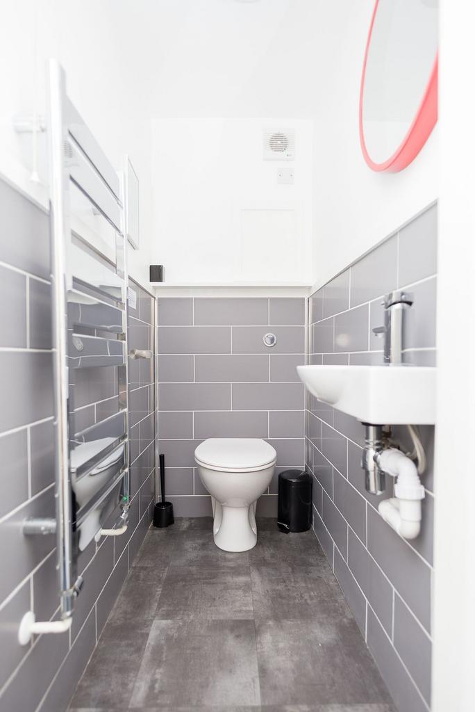 Bright, modern WC with clean grey tiles, compac...