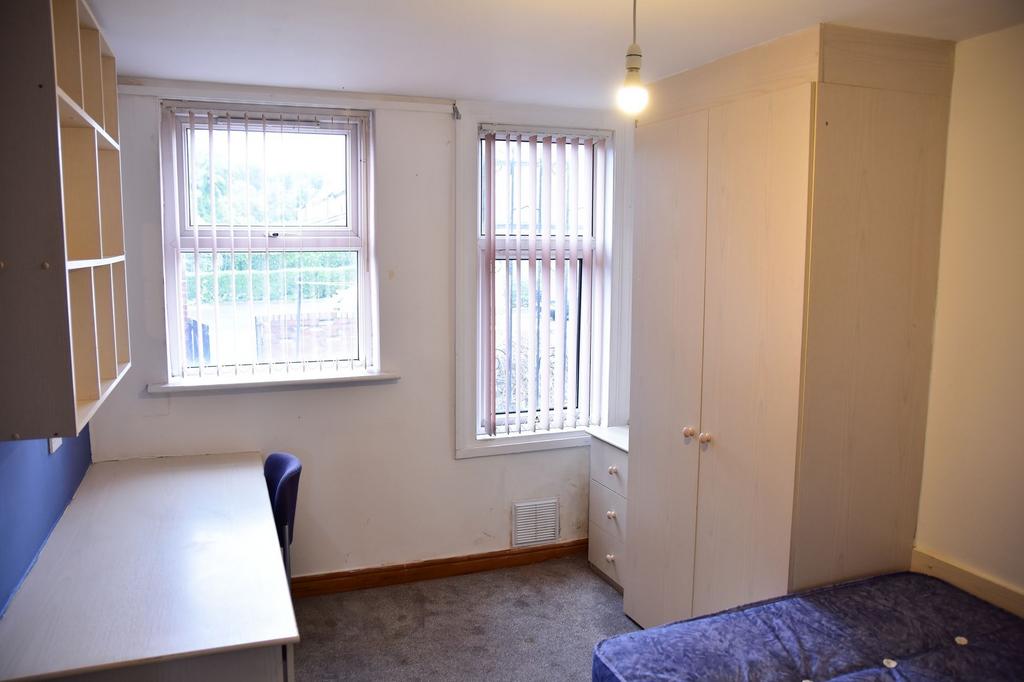 A compact bedroom featuring two windows with ve...