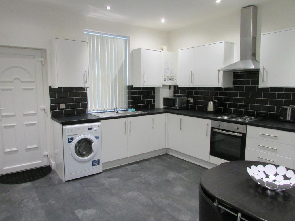 Bright modern kitchen with white cabinets, blac...