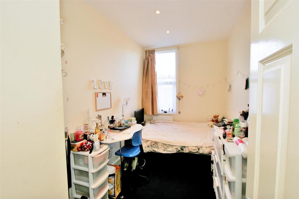 A cozy bedroom with a single bed, cluttered des...