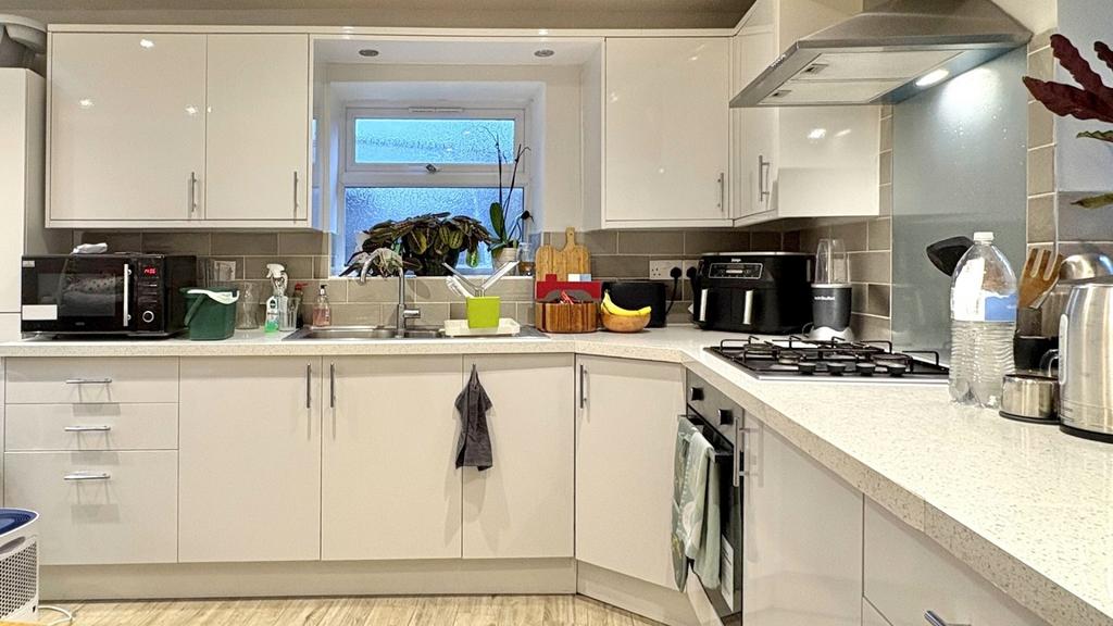 Bright, modern kitchen with white cabinetry, in...