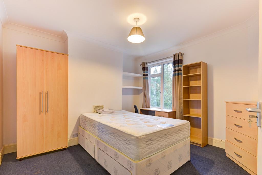 A well-lit, tidy bedroom featuring a comfortabl...