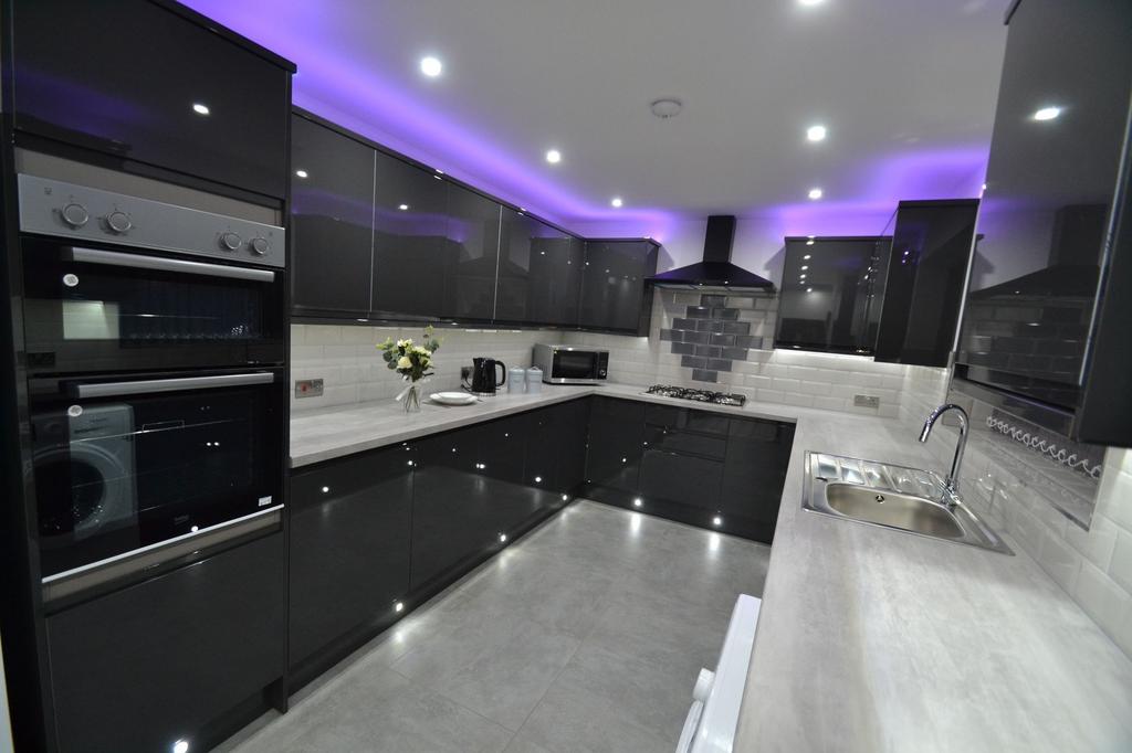 Modern, sleek kitchen featuring glossy black ca...