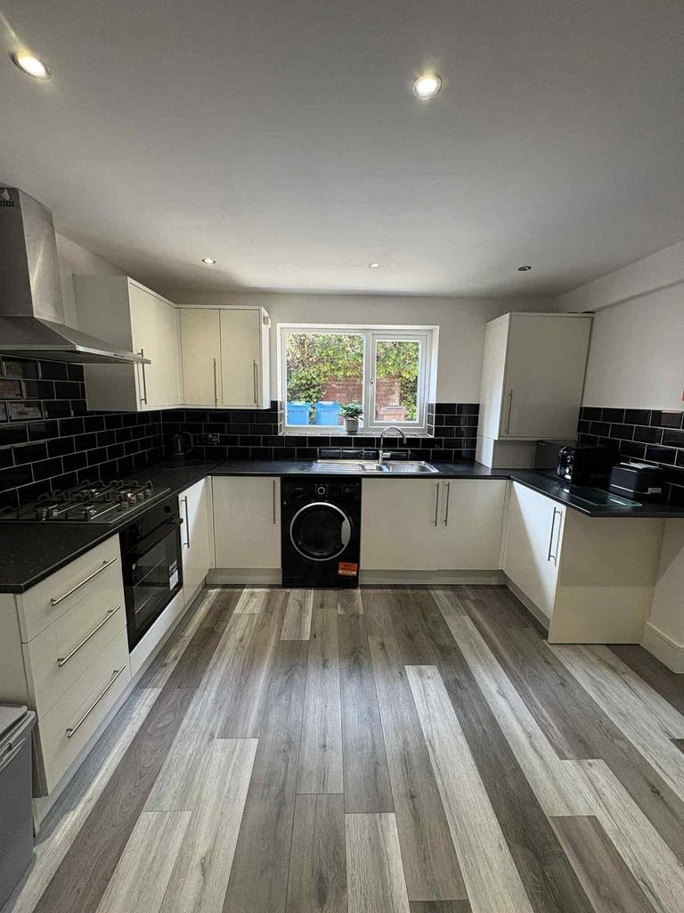 Modern and sleek kitchen with white cabinetry, ...