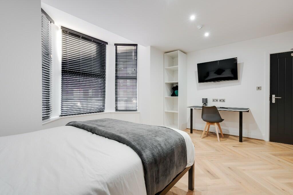 A modern and well-lit bedroom featuring a comfo...