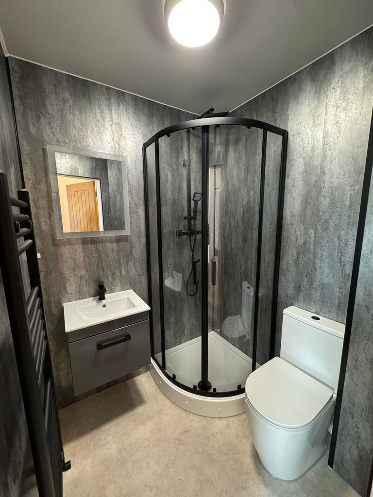 Modern bathroom with a curved glass shower encl...