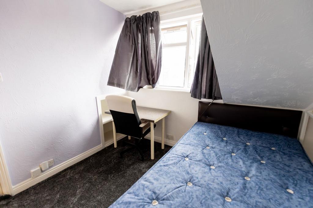 A cozy single bedroom featuring a window with d...