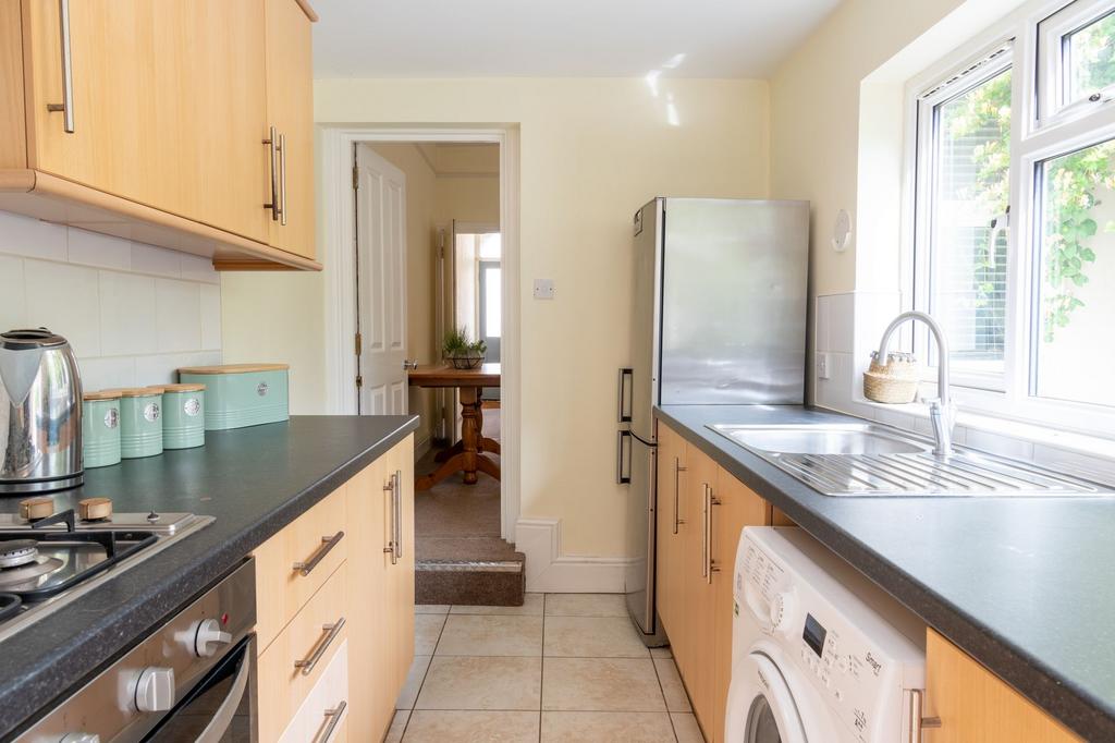 Bright galley kitchen with light wood cabinets,...