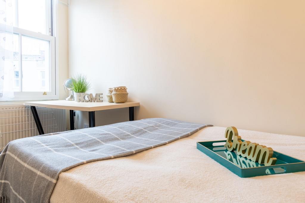 Bright, neatly styled bedroom with a comfortabl...