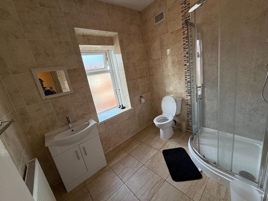 Bright, modern tiled bathroom with a curved gla...