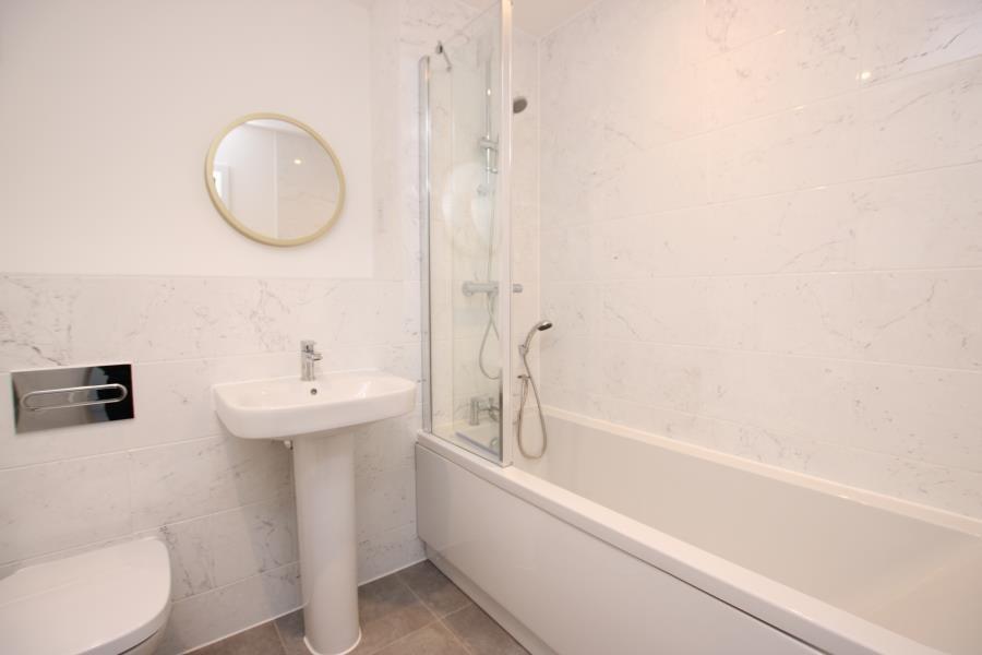 Bright, modern bathroom with a full bathtub and...