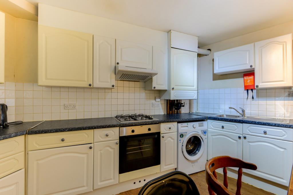 A well-equipped kitchen with white cabinets, a ...