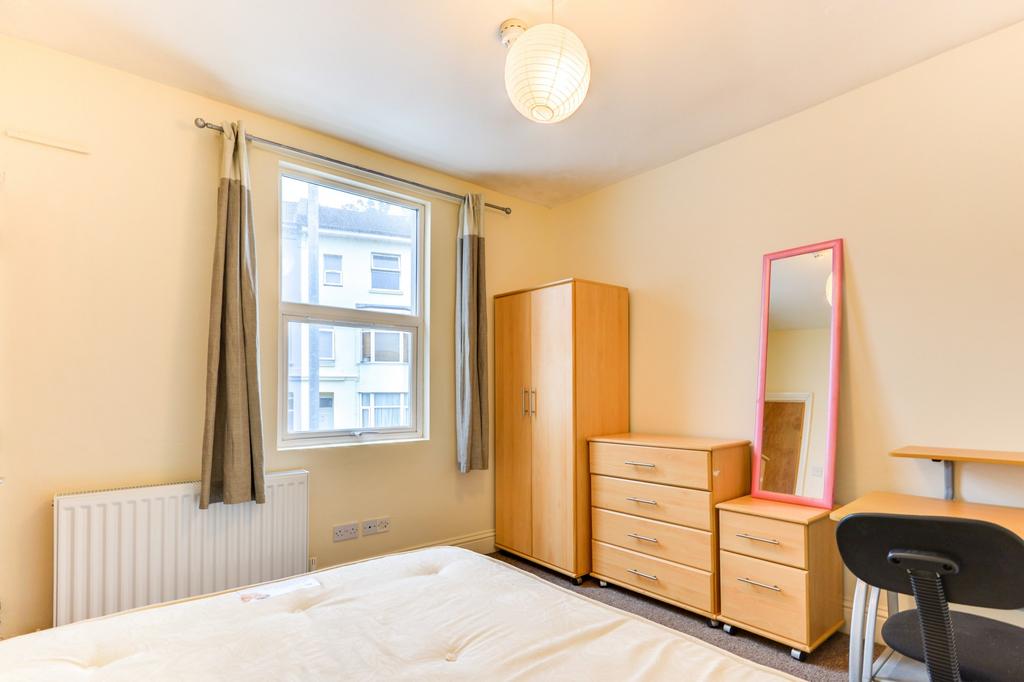 A well-lit, tidy bedroom featuring a large wind...