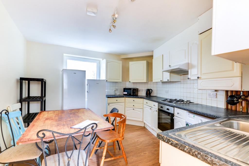 Bright, modern kitchen with white cabinetry, in...