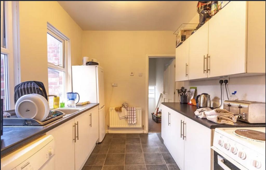 Bright galley kitchen with white cabinets, dark...