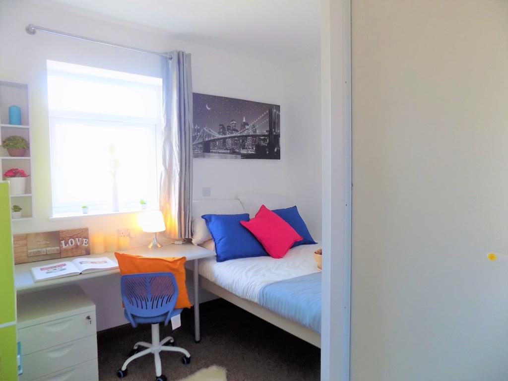 Bright, neatly furnished single bedroom with a ...