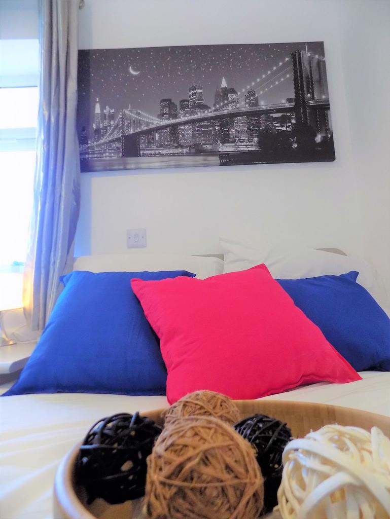 Bright, neatly made bedroom with colourful cush...