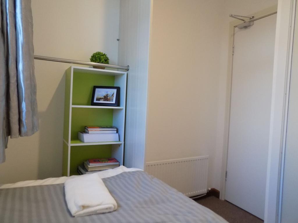 Neat single bedroom with a made bed, compact sh...
