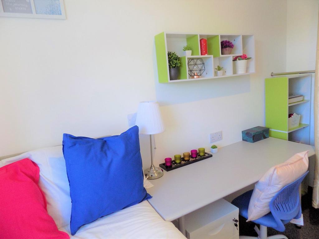 Bright, neatly arranged bedroom with a study ar...