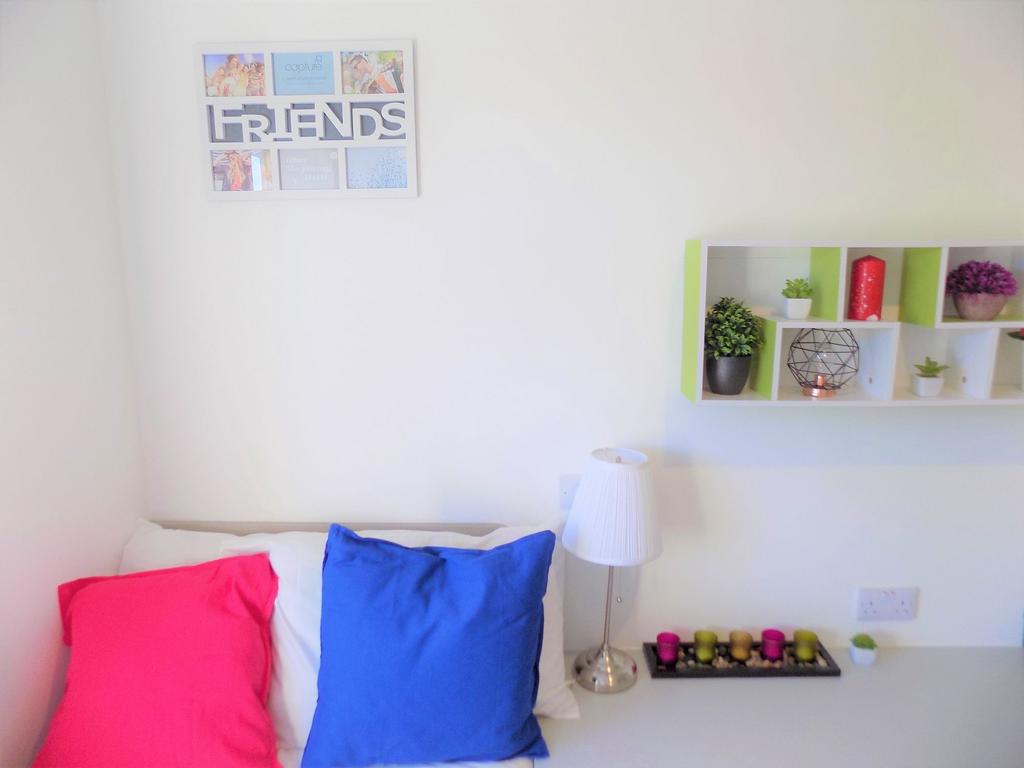 Bright, neatly styled bedroom corner with colou...