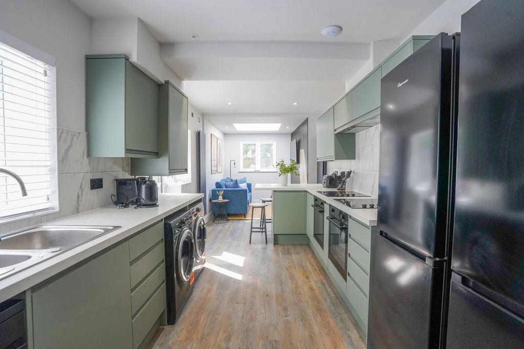 Modern kitchen featuring sleek green cabinets, ...