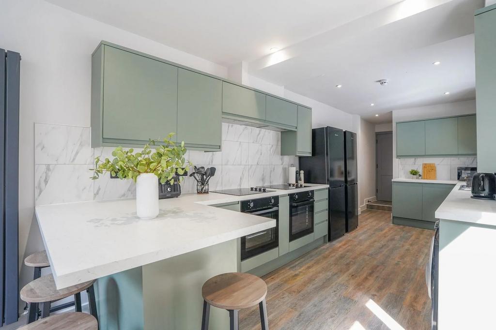 Modern kitchen with stylish green cabinetry, wh...
