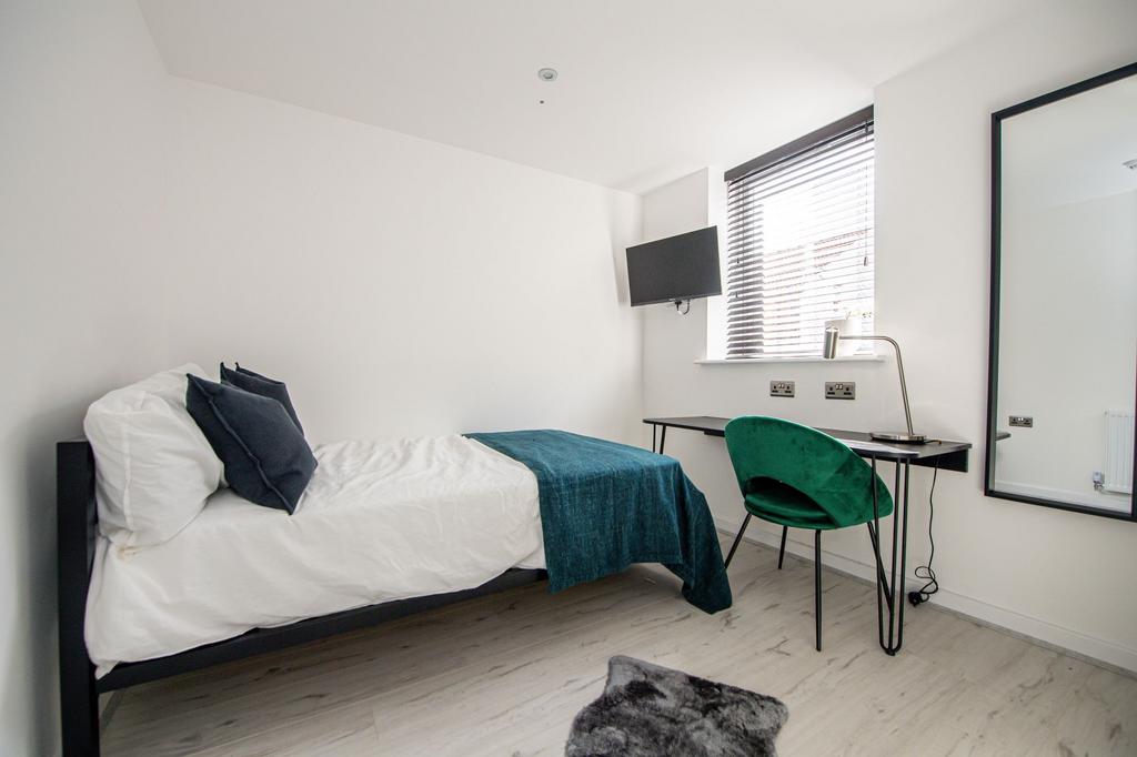 A bright, minimalist single bedroom featuring a...