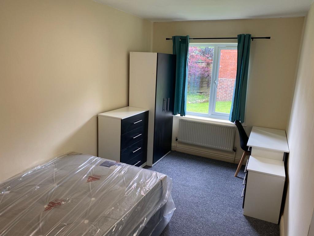 A well-lit, tidy single bedroom featuring a bed...