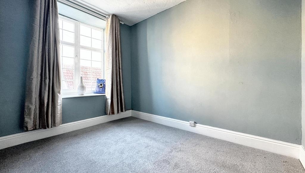 Bright, neutral bedroom with a large sash windo...