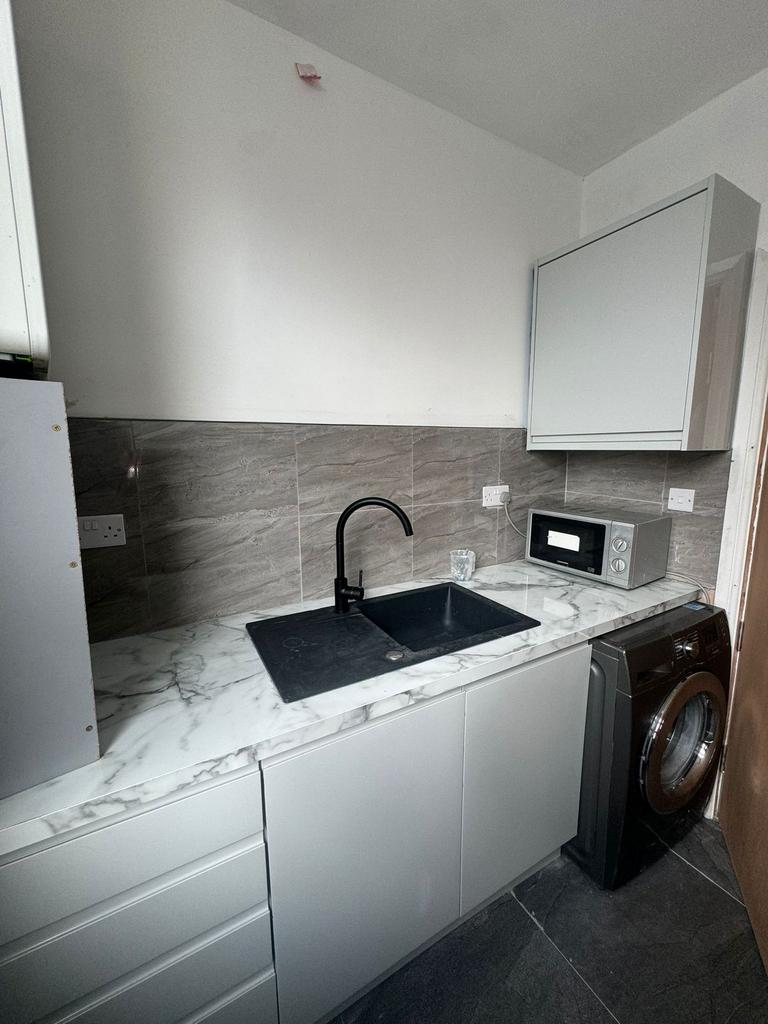 Contemporary kitchenette with marble-effect wor...