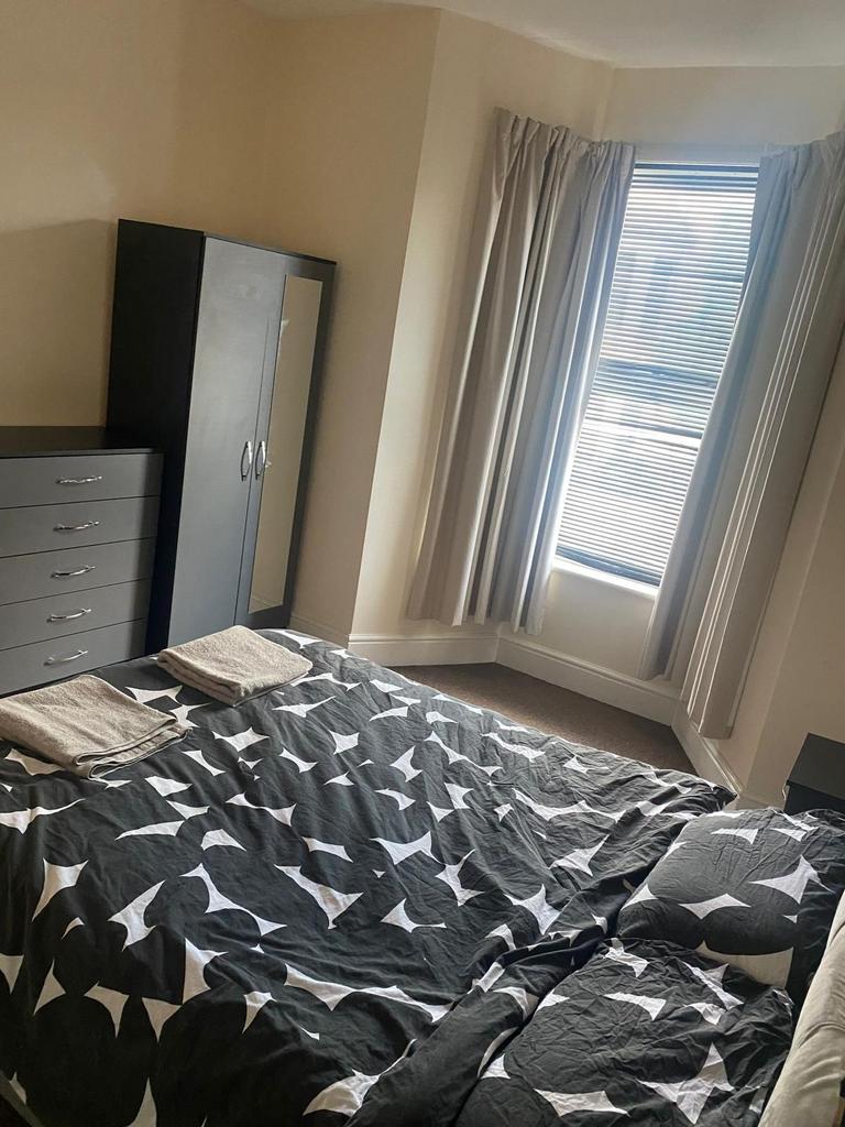 Bright double bedroom with a large window, neut...