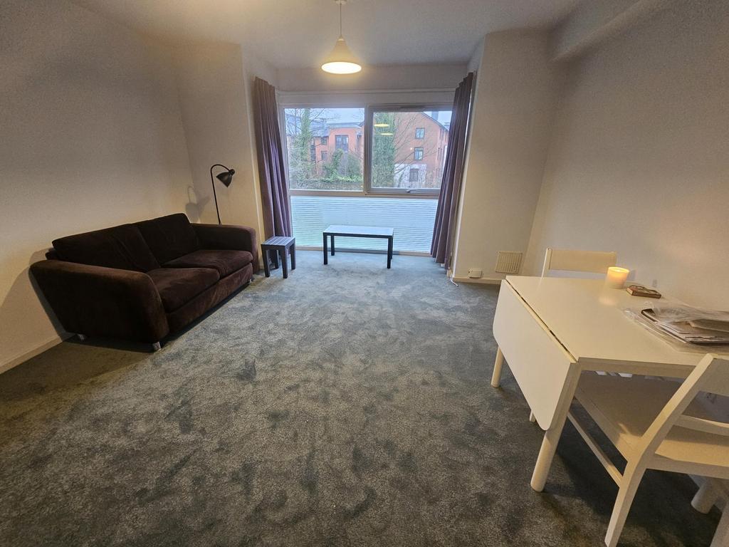 Spacious, carpeted living room with a large win...