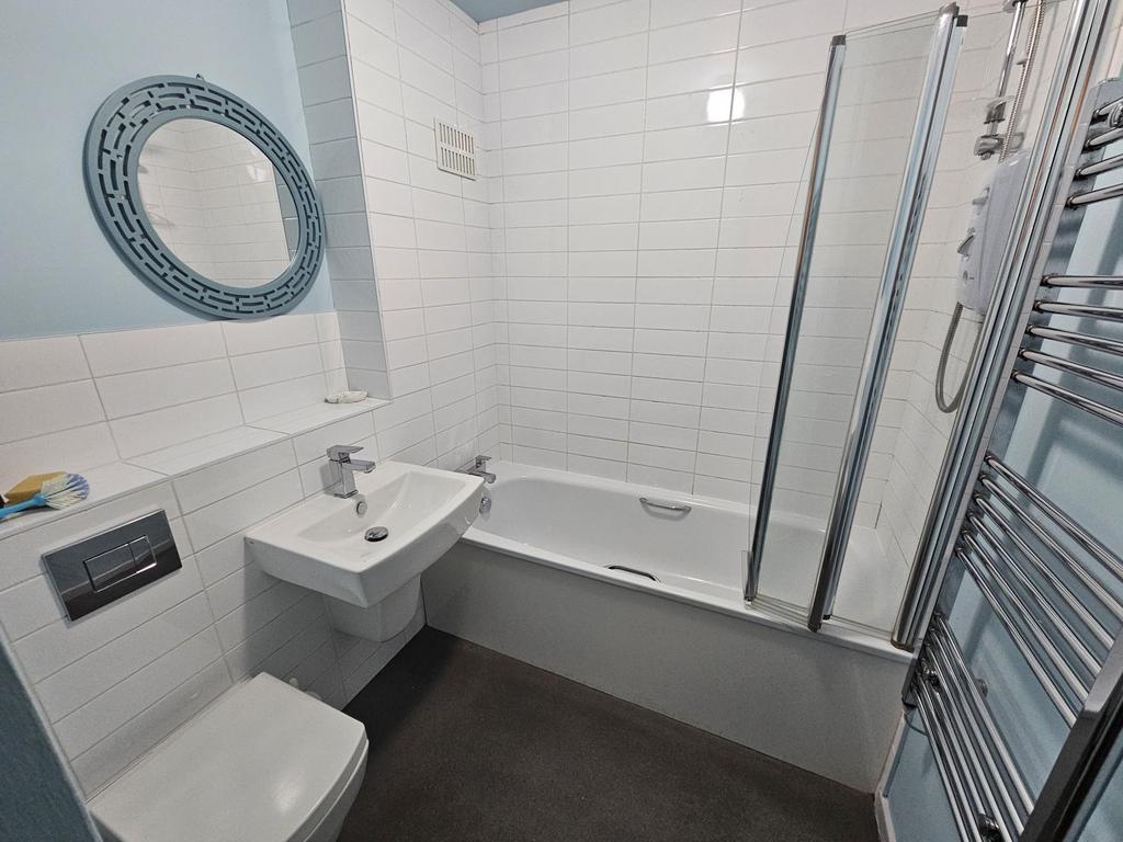 Bright, modern bathroom with a white tiled bath...