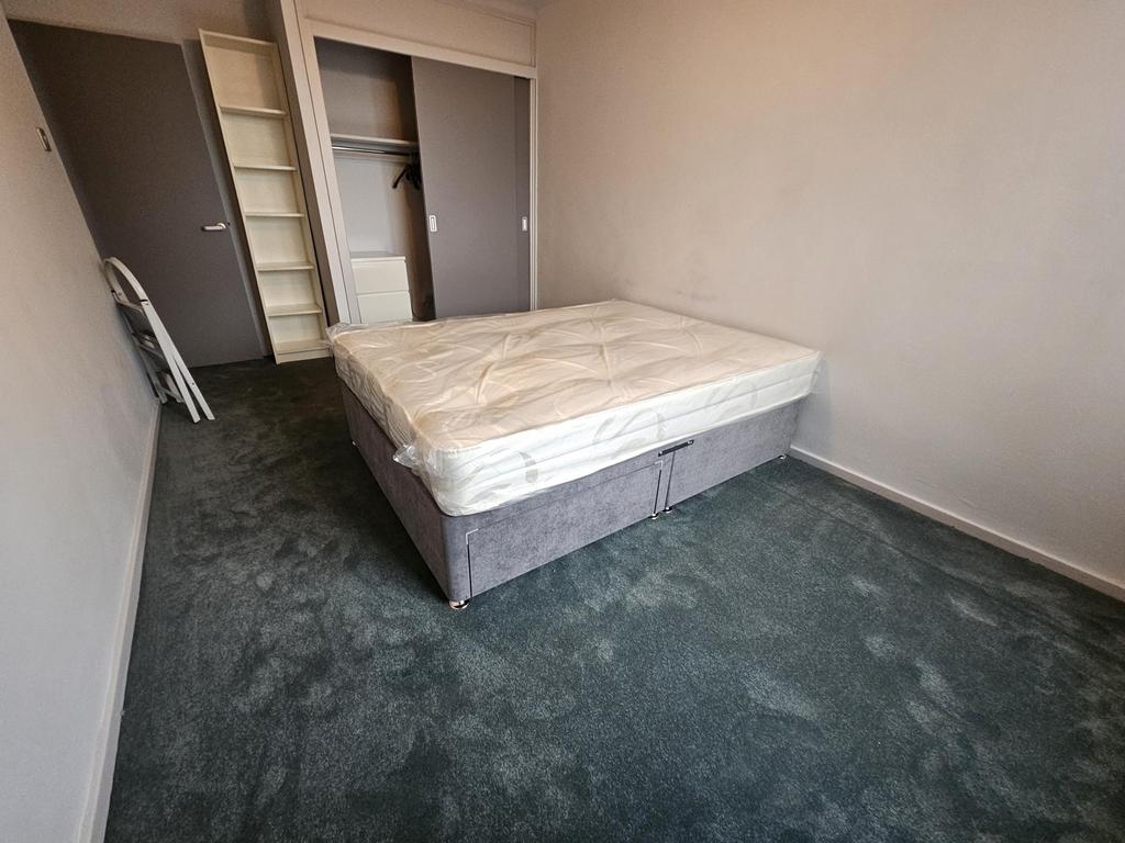 Bright, simply furnished bedroom with a double ...