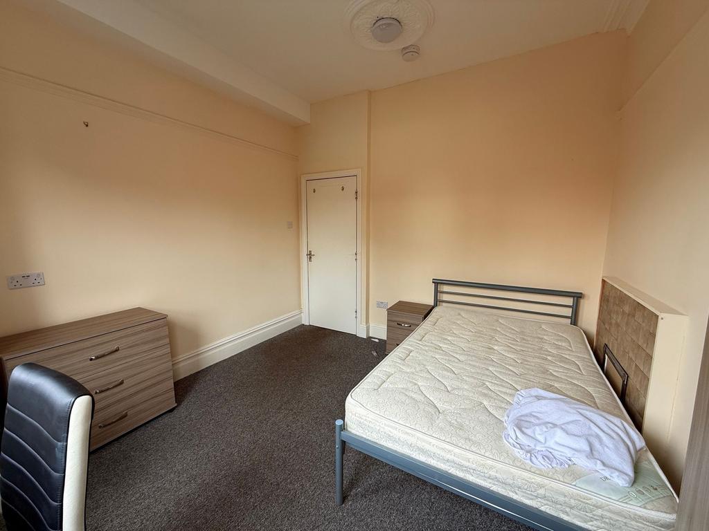 Bright, simply furnished bedroom with a double ...