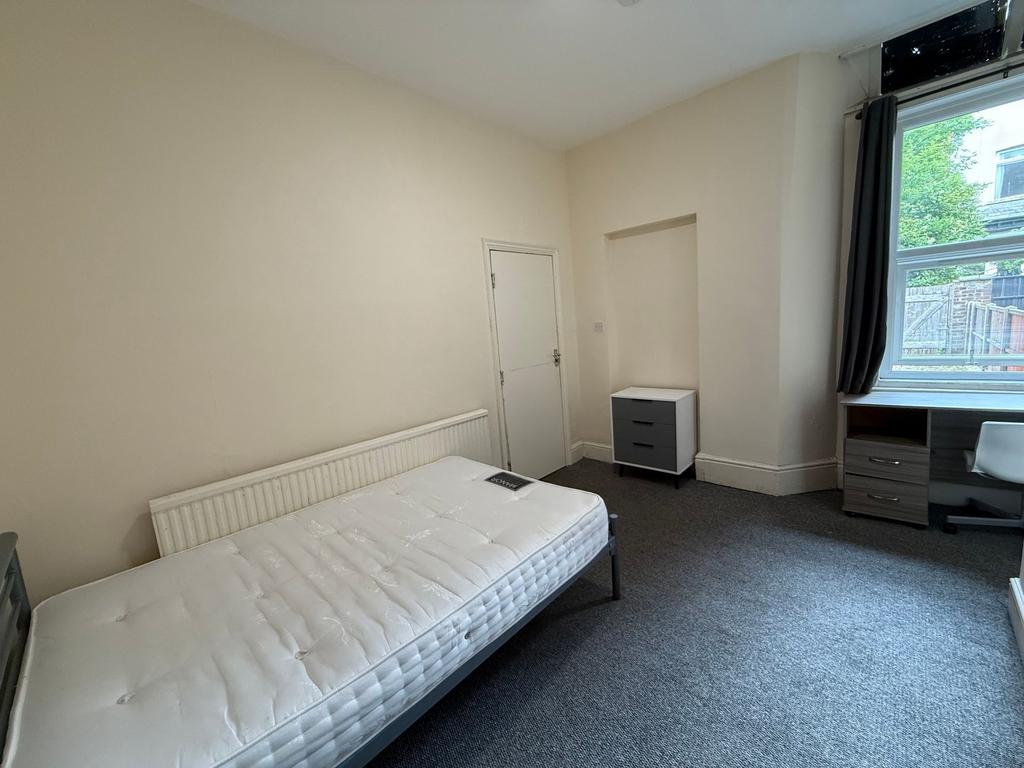 Bright, neutrally decorated bedroom with a comf...