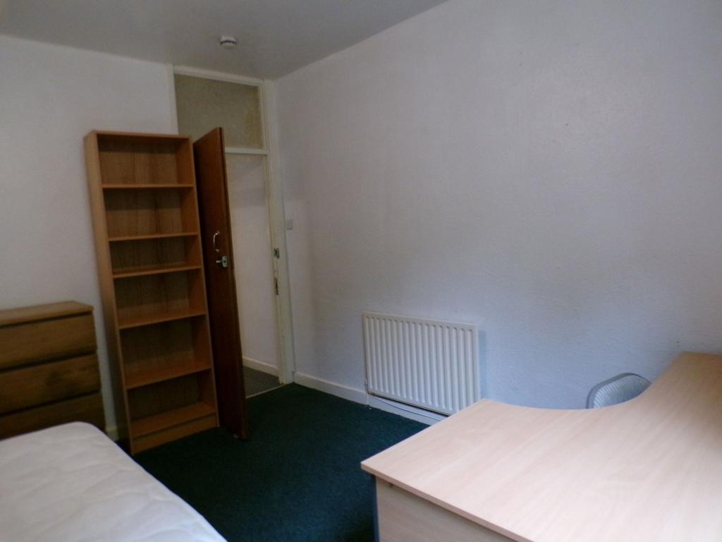 Simple furnished bedroom with a desk, shelving ...