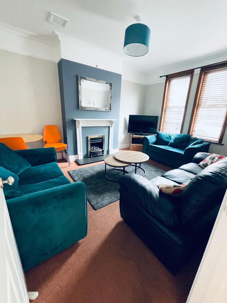 Bright, cosy living room with teal sofas and ma...