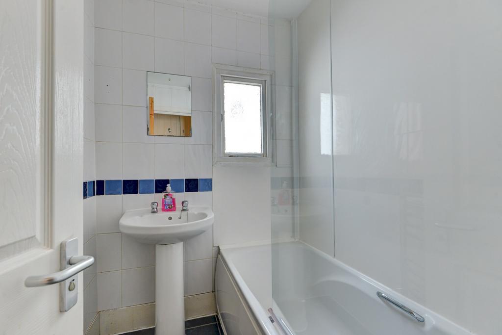 A clean and bright bathroom featuring a bathtub...